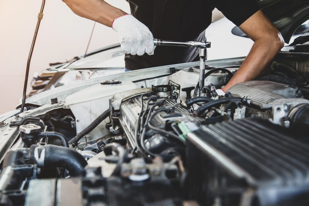 Close-up hand of auto mechanic using wrench to repair a car engine. concepts of car care fix repair service and insurance.